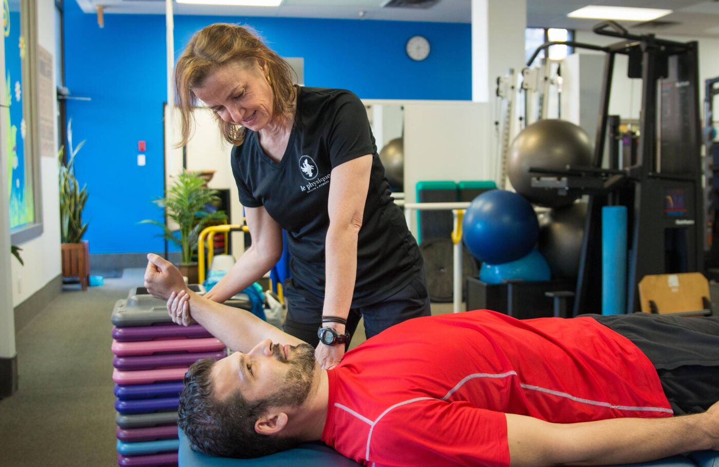 A Le Physique trainer working with a client on a treatment table inside the False Creek studio